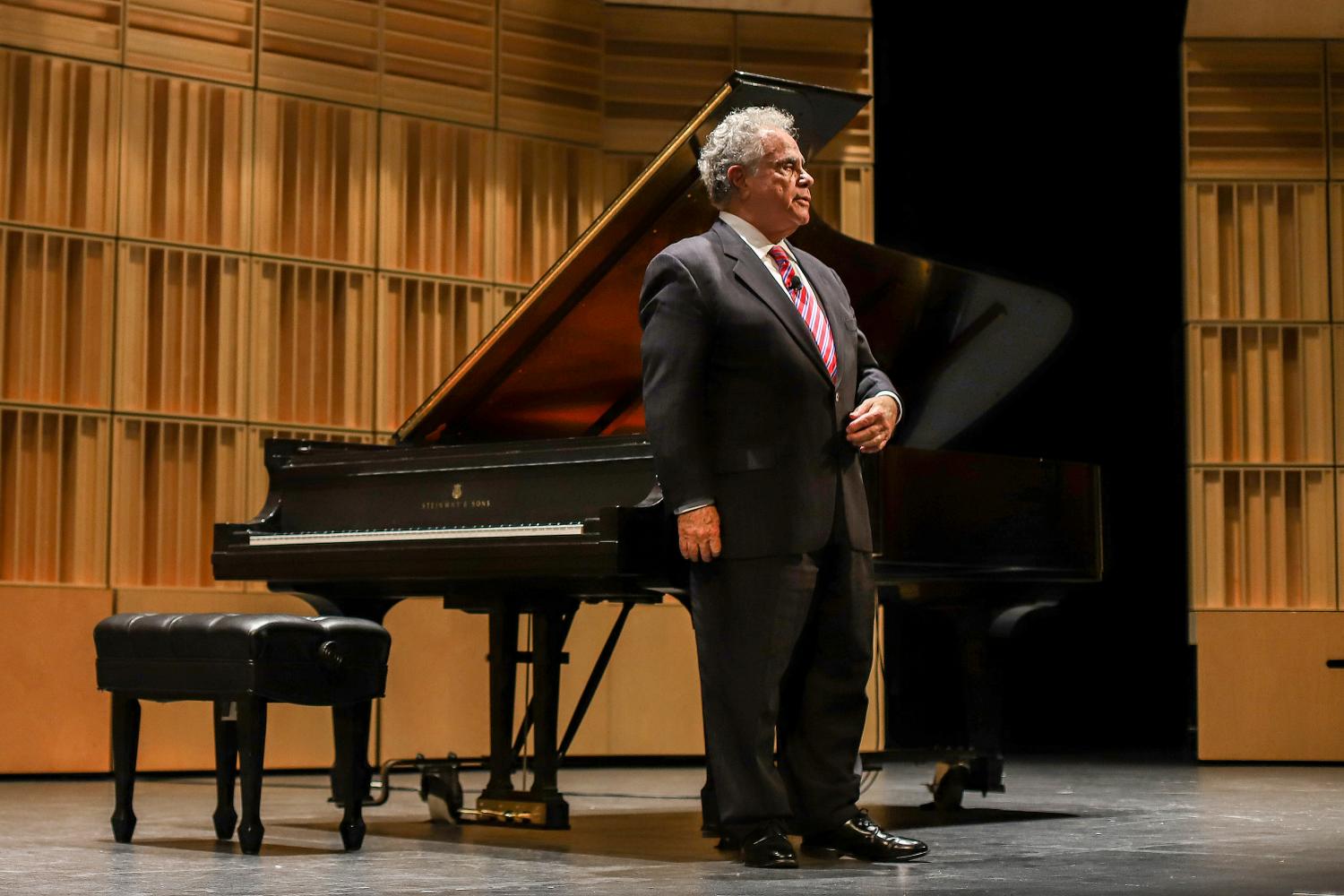 Pianist Jeffrey Siegel stands on stage in front of a piano.