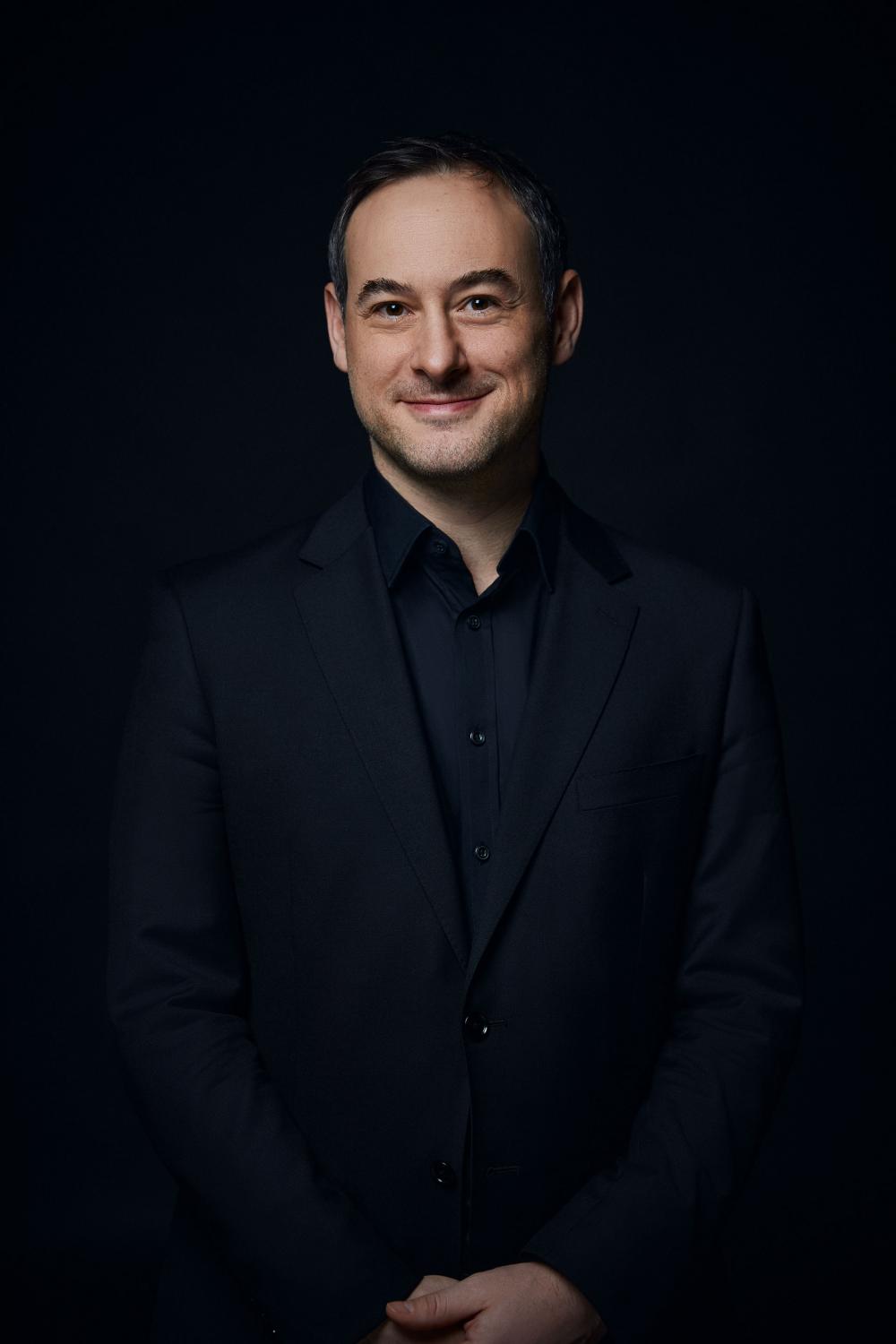 Jonathan Cohen posed in front of a black backdrop.